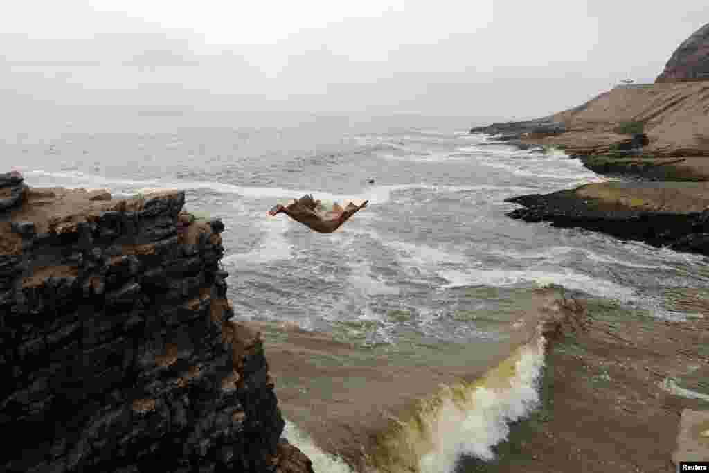 Fernando Jesus Canchari, dressed as a friar jumps from a 13-meter high cliff along Herradura Beach in Lima, Peru, Dec. 7, 2016.