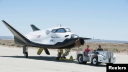 FILE - Sierra Nevada Corporation engineers and technicians prepare the firm's Dream Chaser engineering test vehicle for tow tests on a taxiway at NASA's Dryden Flight Research Center in Palmdale, California, June 27, 2013.