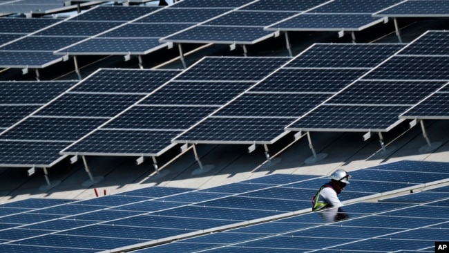 In this Aug. 8, 2019, photo a worker helps to install solar panels onto a roof at the Van Nuys Airport in the Van Nuys section of Los Angeles. On Tuesday, Oct. 8, the Labor Department reports on U.S. producer price inflation in September. (AP Photo/Richard Vogel)