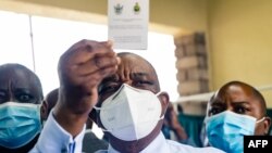 File - In this February 18, 2021 photo, Zimbabwe vice president and Minister of Health Constantino Chiwenga holds up his vaccination certificate after receiving the first shot of Sinopharm COVID-19 vaccine from China.