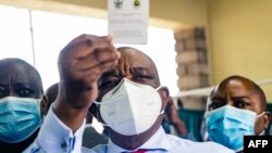 Zimbabwe vice president and Minister of Health Constantino Chiwenga holds up his vaccination certificate after receiving the first shot of Sinopharm in the southern African country which received a donation of 200 000 doses of the COVID-19 vaccine from Ch