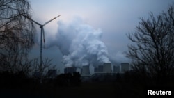 FILE - Water vapor rises from the cooling towers of the Jaenschwalde lignite-fired power plant of Lausitz Energie Bergbau AG beside a wind turbine in Jaenschwalde, Germany, Jan. 24, 2019.