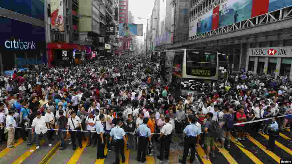 Anti-Occupy Central protesters stand behind a police cordon on Nathan Road at Hong Kong's Mongkok shopping district, demanding the tents set up by pro-democracy protesters to be demolished, Oct. 3, 2014.