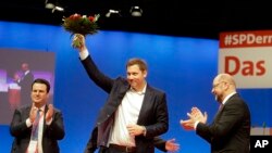 Social Democratic Party, SPD, chairman Martin Schulz, right, and outgoing Secretary General Hubertus Heil, left, applaud to newly elected General Secretary Lars Klingbeil on the second day of the party's convention in Berlin, Friday, Dec. 8, 2017.