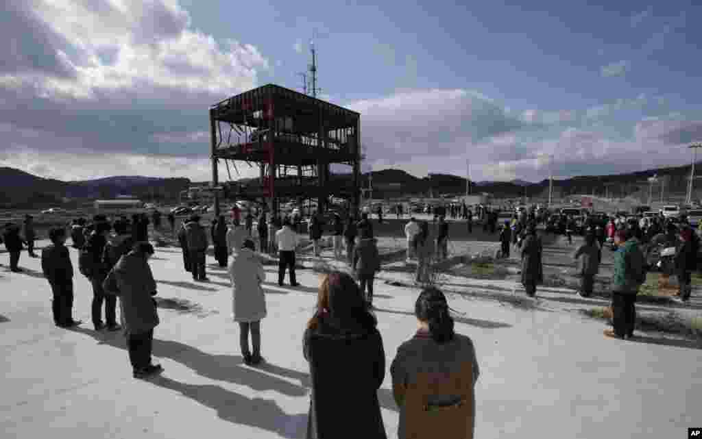 People bow their heads in a moment of silence around what&nbsp;is left of a disaster control center devastated by the March 11, 2011 earthquake and tsunami,&nbsp;Minamisanriku, Miyagi prefecture, Japan, March 11, 2013.