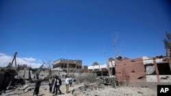 یمنی شہری صنعا میں ایک فضائی حملے سے ہونے والے نقصان کا جائزہ لے رہے ہیں۔ فائل فوٹو