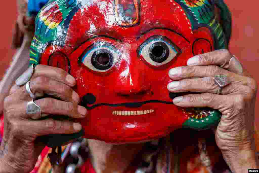A person fixes a clay mask while preparing to take part in a deity's procession during the Shikali festival at Khokana, in Lalitpur, Nepal.