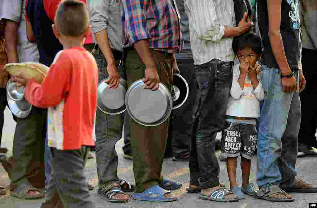 Pessoas esperam para receber comida e ajuda depois do terramoto no Nepal num campo de refugiados em Katmandu. Aproximadamente 8,500 pessoas são confirmadas mortos na crise, que destruiu mais do meio milhão casas, e deixou um número incrível de pessoas sem abrigo.