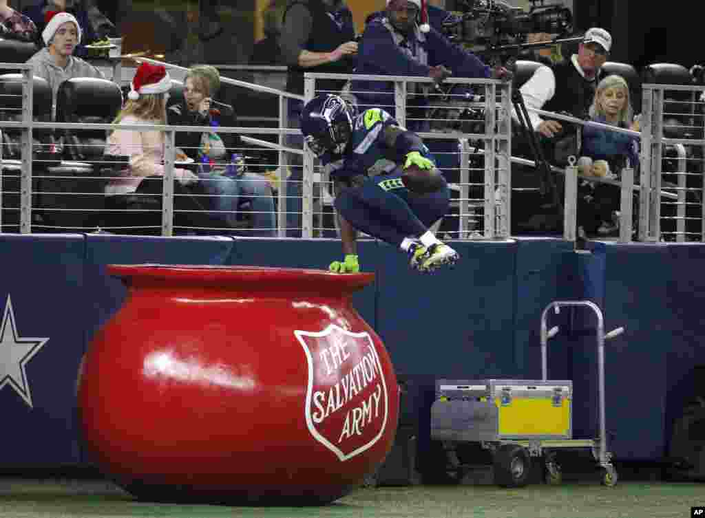 Seattle Seahawks cornerback Justin Coleman (28) leaps into The Salvation Army kettle after returning a Dallas Cowboys&#39; Dak Prescott interception for a touchdown in the second half of an NFL football game, Dec. 24, 2017, in Arlington, Texas.