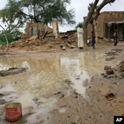 People standing near homes destroyed by flooding near Zinder.