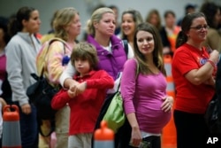 FILE - Nicole Andreacchio, second right, who is seven months pregnant waits in line to receive the swine flu vaccine from the Montgomery County Health Department at Congregation Beth Or in Maple Glen, Penn.
