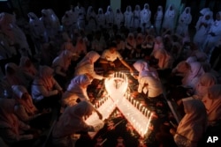 Indonesian medical students light candles during a vigil commemorating World AIDS day in Surabaya, East Java, Indonesia, Monday, Dec. 1, 2015. World AIDS Day is observed on Dec. 1 every year to increase awareness about AIDS. (AP Photo/Trisnadi)