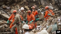 Firefighters carry away a body from the rubble after a building collapsed in downtown Rio de Janeiro, Brazil, Friday, Jan. 27, 2012. The building collapsed on Wednesday.