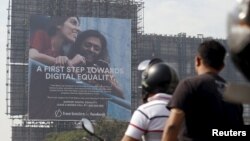 FILE - Motorists ride past a billboard displaying Facebook's Free Basics initiative in Mumbai, India.