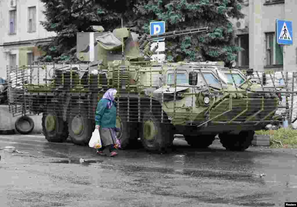 A local resident walks past a Ukrainian armored vehicle in the eastern Ukrainian city of Kramatorsk, July 7, 2014.