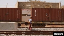 FILE - A woman walks along newly built tracks of the high-speed railway in Mbao, on the outskirts of Dakar, Senegal, Feb. 12, 2019. 