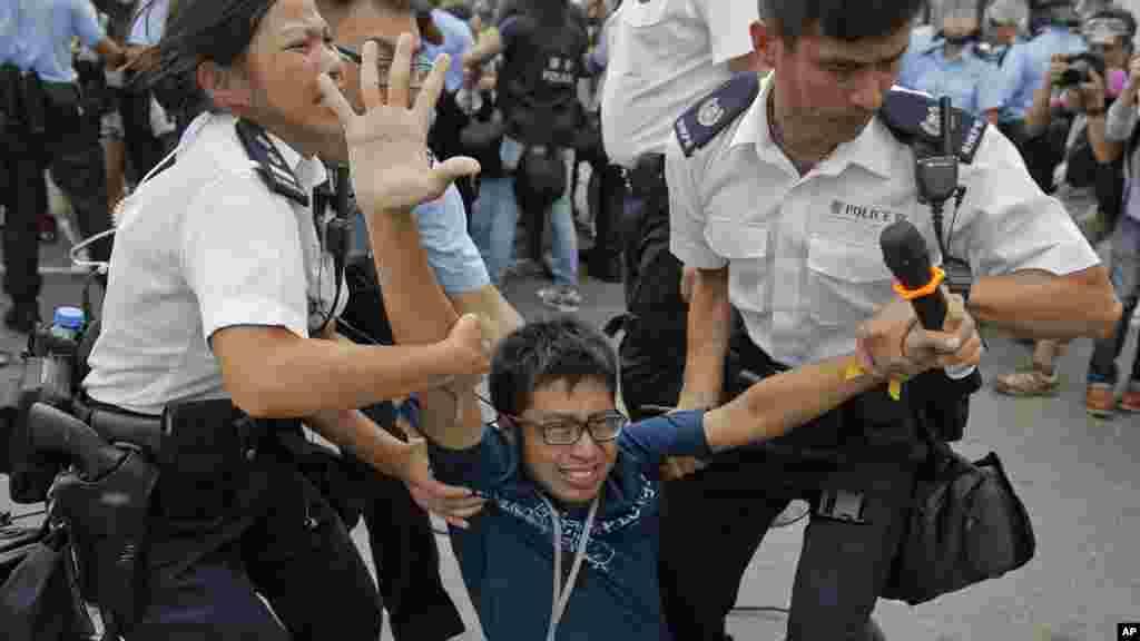 Un des manifestants pro-démocratie emmenés de force par des policiers, le 3 octobre 2014. 