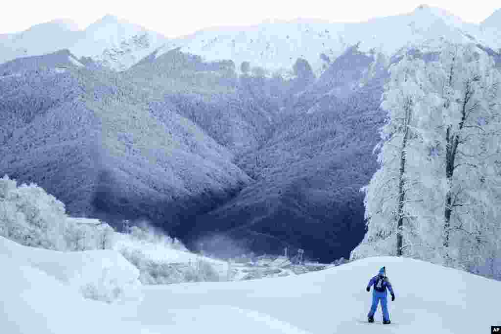 A volunteer rides his snowboard along the practice slope for the alpine ski course of the 2014 Winter Olympics in Krasnaya Polyana, Russia. 