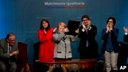 Chile's President Michelle Bachelet holds up a portfolio containing her signed proposal for a same-sex marriage bill at La Moneda presidential palace in Santiago, Chile, Aug. 28, 2017.