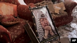 FILE - A poster of Palestinian leader Yasser Arafat is seen on the rubble of a destroyed house in the Bureij refugee camp in the central Gaza Strip, Aug. 1, 2014.