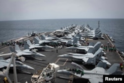 FILE - Sailors check for foreign objects and debris on the flight deck of the Nimitz-class aircraft carrier USS Abraham Lincoln in the Arabian Sea, May 19, 2019.