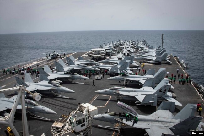 FILE - Sailors check for foreign objects and debris on the flight deck of the Nimitz-class aircraft carrier USS Abraham Lincoln in the Arabian Sea, May 19, 2019.