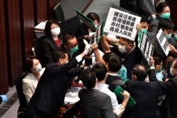 Hong Kong pro-democracy lawmakers holding up placards are blocked by security as they protest during a House Committee meeting, chaired by pro-Beijing lawmaker Starry Lee (L-in white jacket)
