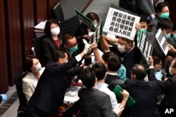 Hong Kong pro-democracy lawmakers holding up placards are blocked by security as they protest during a House Committee meeting, chaired by pro-Beijing lawmaker Starry Lee (L-in white jacket)