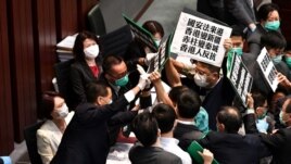 Hong Kong pro-democracy lawmakers holding up placards are blocked by security as they protest during a House Committee meeting, chaired by pro-Beijing lawmaker Starry Lee (L-in white jacket)