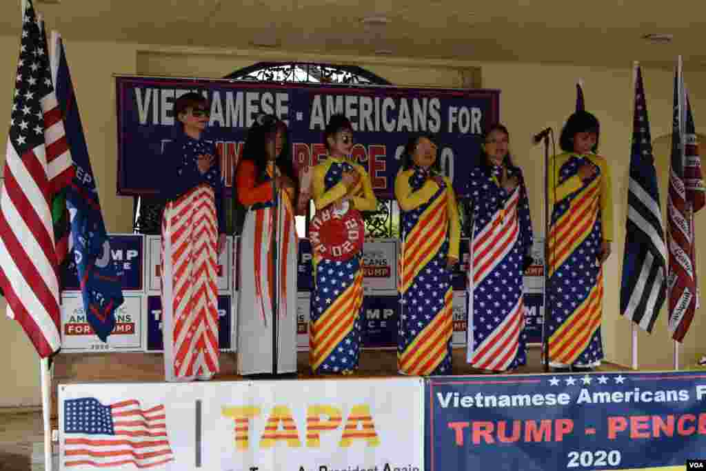 Cuộc tập hợp được tổ chức bởi hai hội chính trị do một số người Việt ở Florida lập ra để vận động Tổng thống Trump tái đắc cử, hợp tác cùng Asian Pacific Americans for Trump, một nhánh của ban vận động tranh cử Trump nhắm mục tiêu vận động khối cử tri người Mỹ gốc Á và các đảo quốc Thái Bình Dương. Trong ảnh, các thành viên của ban tổ chức đang hát quốc ca của Mỹ và Việt Nam Cộng Hòa.