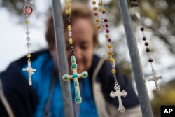 Lupe Cantu, of McAllen Valley, Texas, hangs rosary beads on a barricade along Benjamin Franklin Parkway as she waits for Mass delivered by Pope Francis in Philadelphia, Sept. 27, 2015.