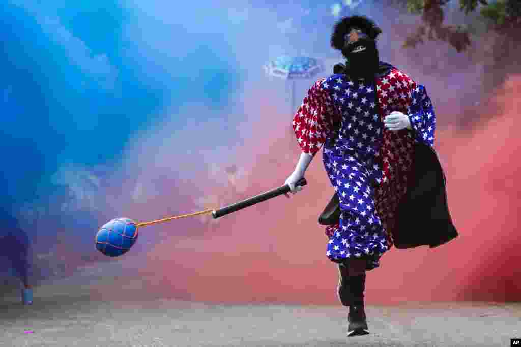 A member of a “bate-bola” or ball hitters group - men who dress up in exuberant, identical, hand-made costumes known as “fantasias” - runs past during a brief appearance as part of a Carnival tradition despite restrictions due to the COVID-19 pandemic in in Rio de Janeiro, Brazil, Feb. 13, 2021.