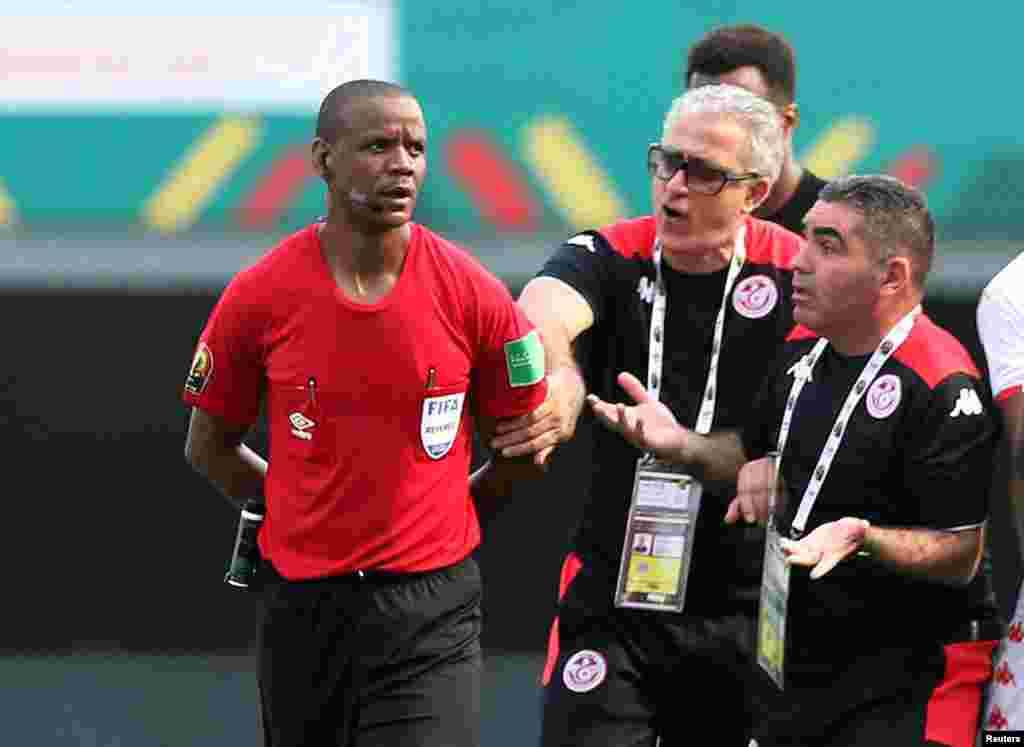 Tunisia coach Mondher Kebaier (M) discusses with the referee Janny Sikazwe after the match.