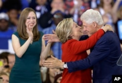 Democratic presidential candidate Hillary Clinton hugs her husband, former President Bill Clinton as their daughter Chelsea Clinton looks on during a campaign rally in Raleigh, N.C., Nov. 8, 2016.