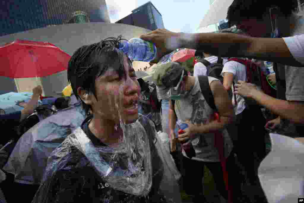 A student protester is overcome by pepper spray from riot police as thousands of protesters surround the government headquarters in Hong Kong.