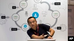 An attendee sits near a diagram illustrating cloud security during the 4th China Internet Security Conference (ISC) in Beijing, Aug. 16, 2016.