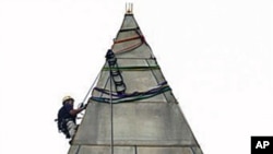 Dave Megerle attaches ropes to the top of the Washington Monument, from which four people will rappel down the sides to survey the extent of damage sustained to the monument from the August 23 earthquake, on the National Mall, in Washington, September 27,