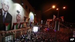 Palestinians watch their President Mahmoud Abbas on TV as he delivers his speech at the General Assembly of the United Nations, in the West Bank city of Hebron, September 23, 2011.