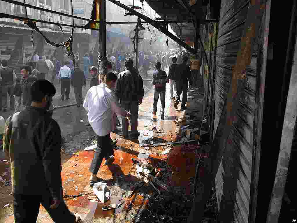 Syrians walk through blood and debris after a raid by Syrian troops in Damascus. (AP)