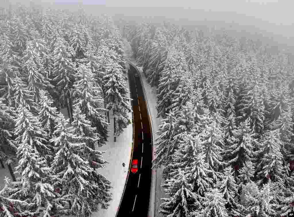 A car drives between snow covered trees in the Taunus region near Frankfurt, Germany.