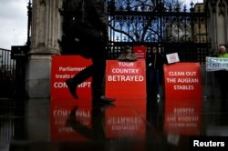 FILE - A person walks past pro-Brexit protesters outside the Houses of Parliament, April 4, 2019.