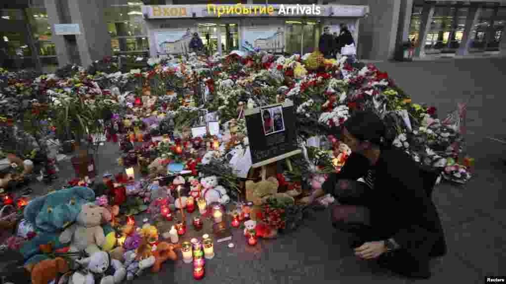 A woman lays flowers at a makeshift memorial for victims of a Russian airliner which crashed in Egypt, outside Pulkovo Airport in St. Petersburg, Russia, Nov. 4, 2015.