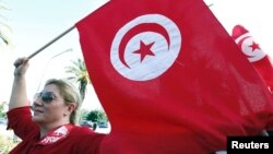 A woman waves a Tunisia flag during a rally to protest against religious and political violence in Tunis, Oct. 22, 2012.