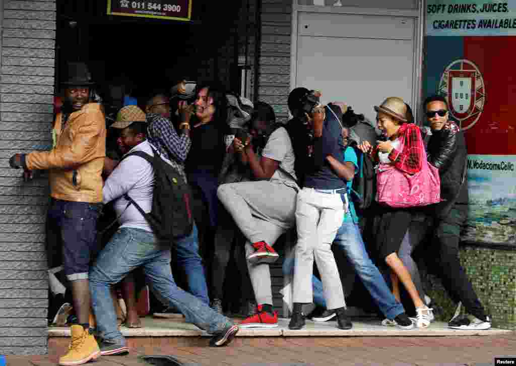 Students demanding free education react as they are fired at by riot police officers during a protest outside the University of the Witwatersrand at Braamfontein, in Johannesburg, South Africa.