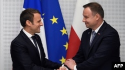 FILE - FILE - French President Emmanuel Macron (L) and Polish President Andrzej Duda shake hands during their bilateral meeting on the sidelines of the NATO (North Atlantic Treaty Organization) summit in Brussels, on May 25, 2017.