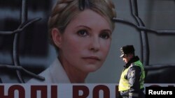 An Interior Ministry officer walks past a board displaying a portrait of jailed former Ukrainian Prime Minister and opposition leader Yulia Tymoshenko at a protest tent camp set up by her supporters in central Kyiv, Nov. 18, 2013.