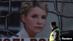 An Interior Ministry officer walks past a board displaying a portrait of jailed former Ukrainian Prime Minister and opposition leader Yulia Tymoshenko at a protest tent camp set up by her supporters in central Kyiv, Nov. 18, 2013.