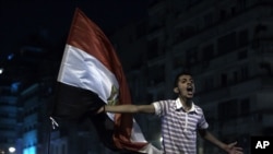 A youth shouts next to an Egyptian flag as the revolutionary youth of Egypt return to Tahrir to protest the outcome of the Egyptian presidential election, Cairo, Egypt, May 28, 2012.