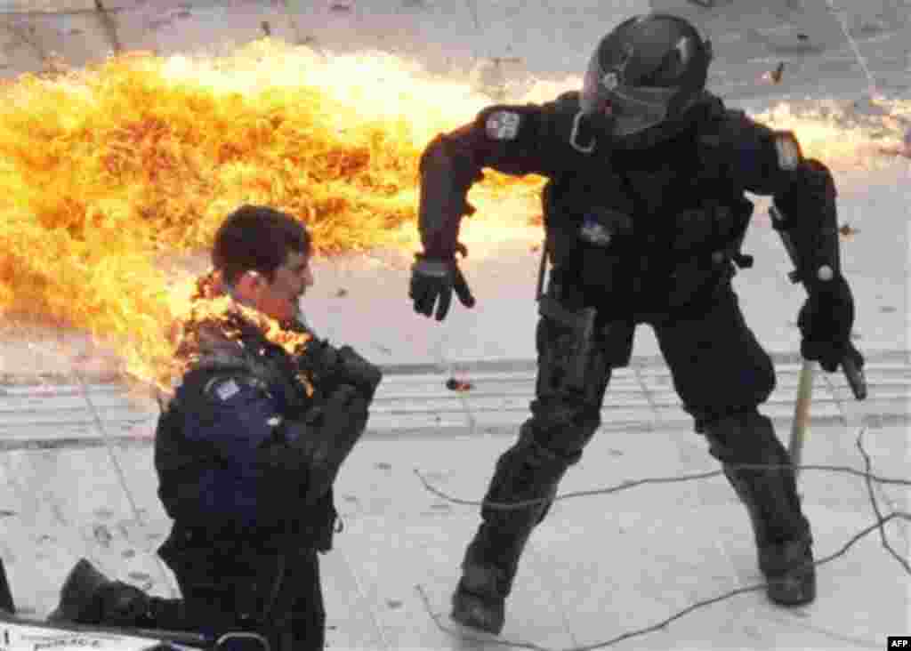 A motorcycle policeman burns as his colleague, left, tries to help him after protesters threw a petrol bomb in Athens, Wednesday, Feb. 23, 2011. Scores of youths hurled rocks and petrol bombs at riot police after clashes broke out Wednesday during a mass 