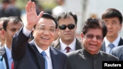 Chinese Premier Li Keqiang waves as he is received by Indian junior minister for external affairs, E. Ahamed, right, after he arrived in New Delhi, India, May 19, 2013. 